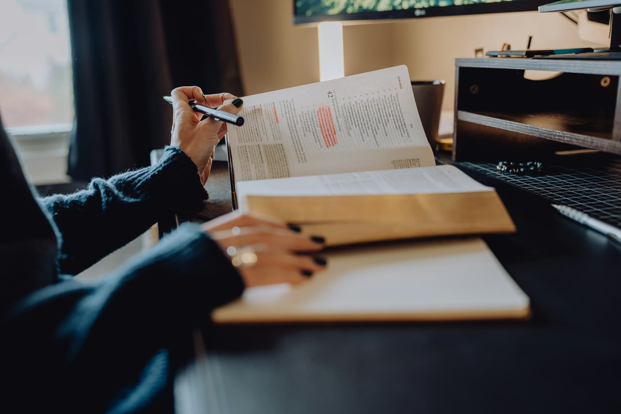 Hand met pen bij een opengeslagen boek op een bureau