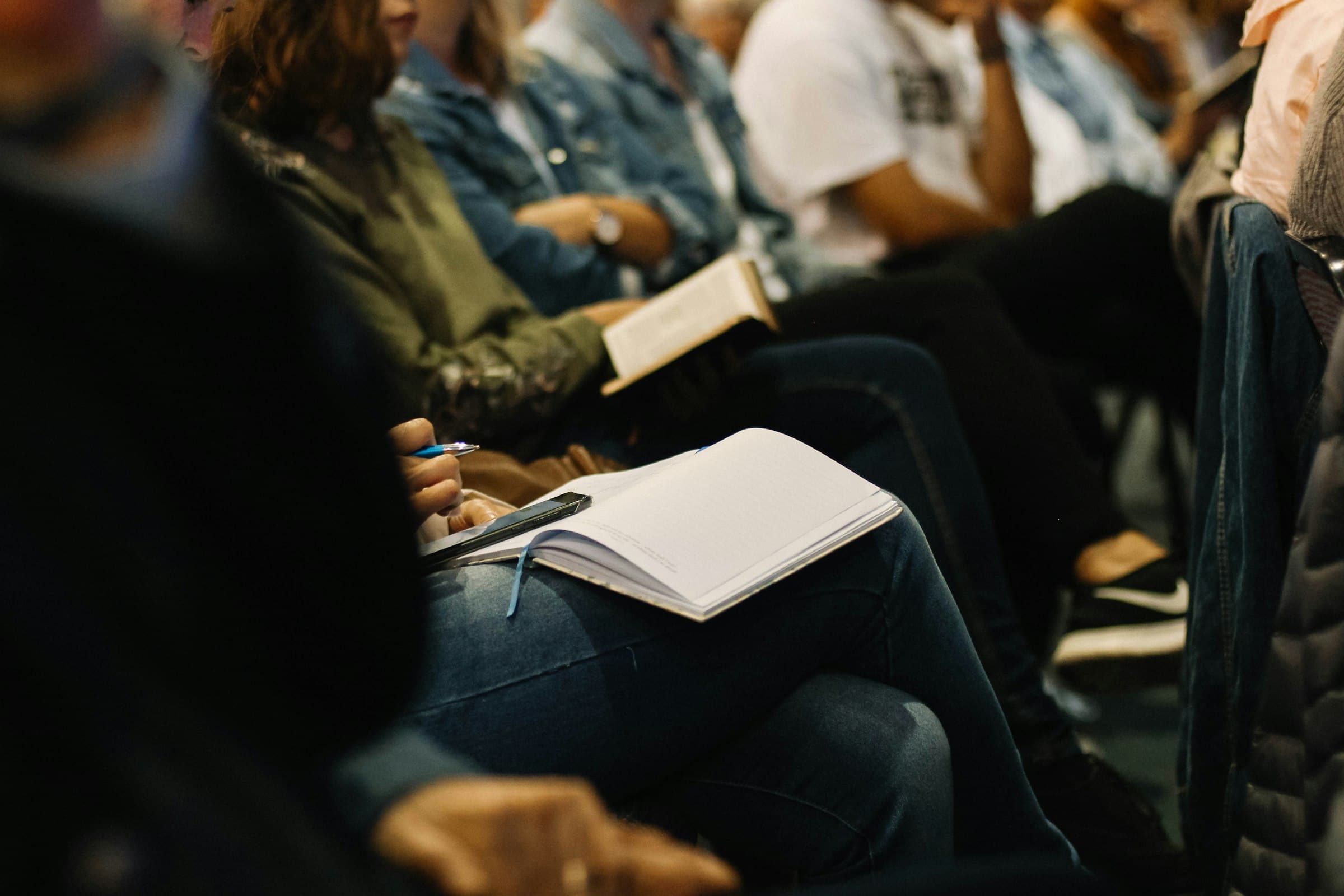 Toehoorders met notitieboekjes op schoot tijdens een lezing